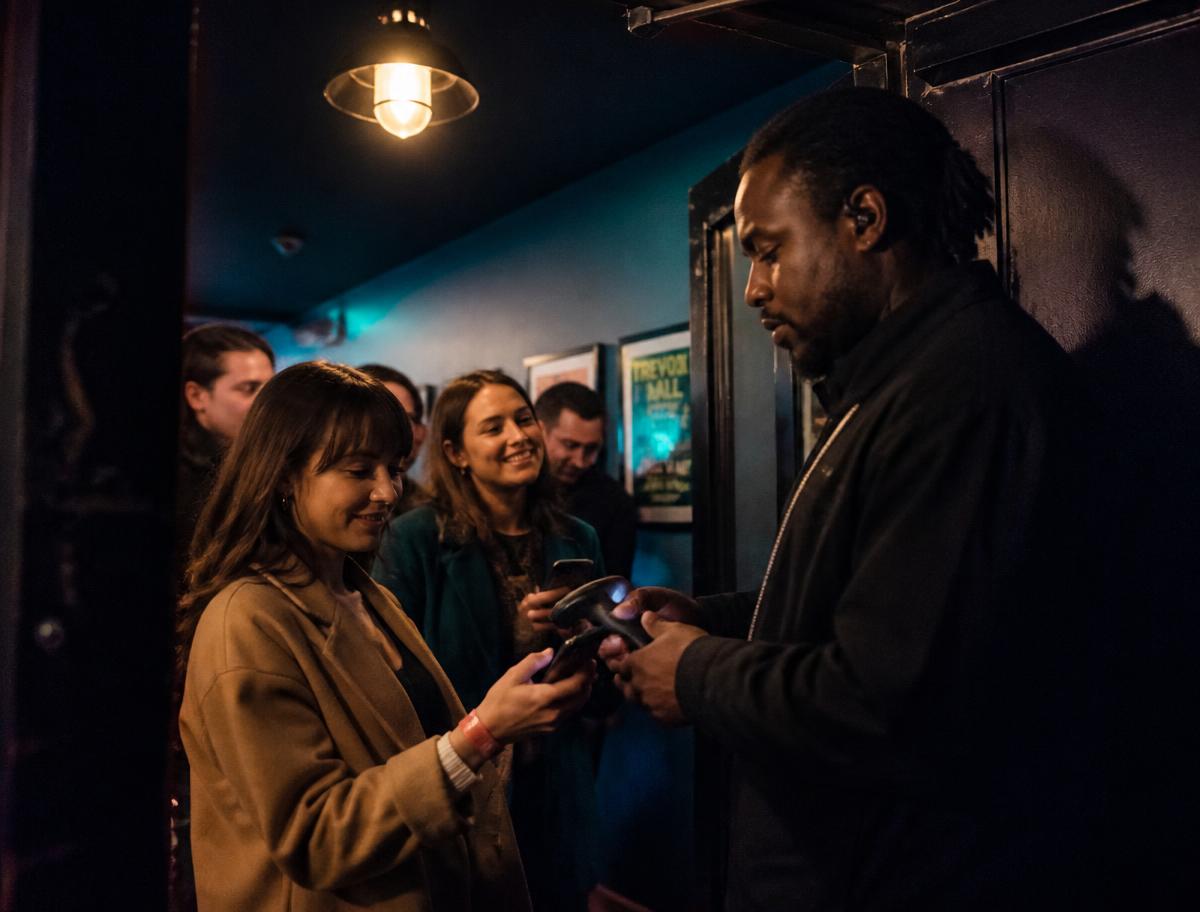 A door host scanning a phone ticket at a small club entrance